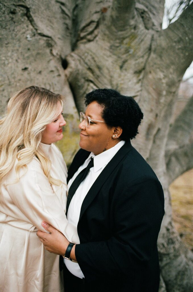 Two brides embrace and smile at each other, captured on film