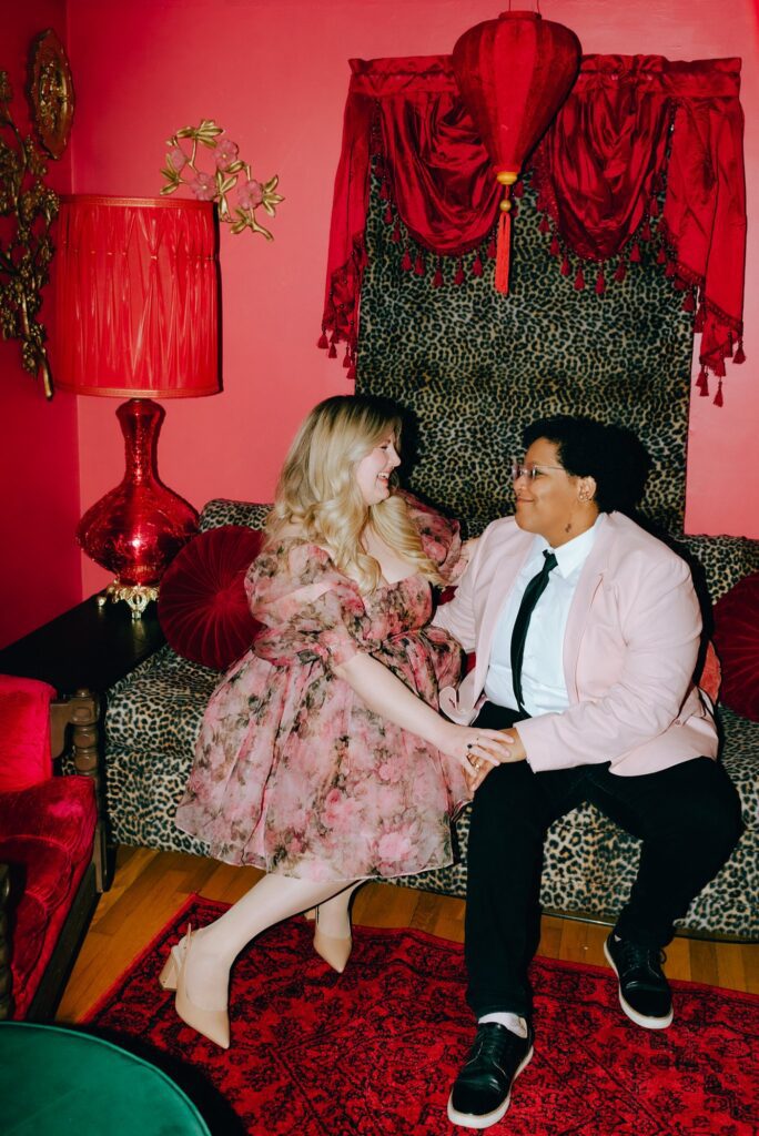Two brides sit together on a vintage leopard print couch