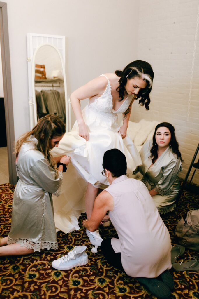 A wedding party helps a bride put on her shoes