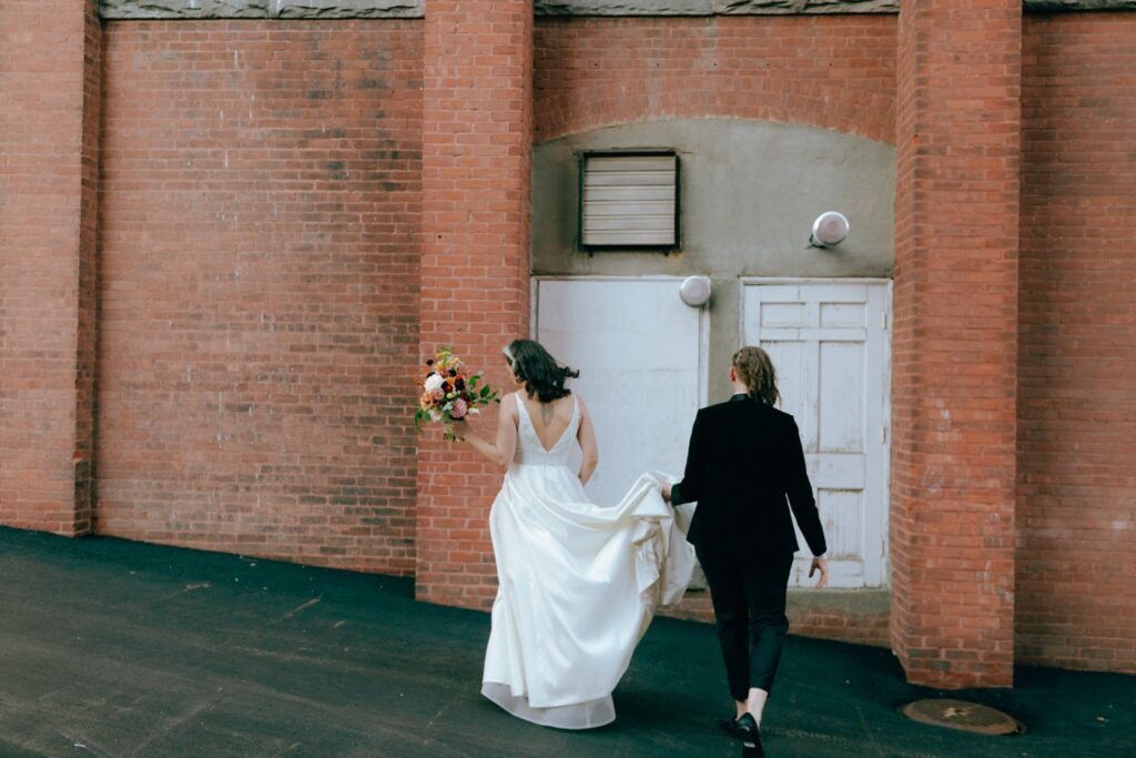 a bride helps her bride walk by holding up her dress train