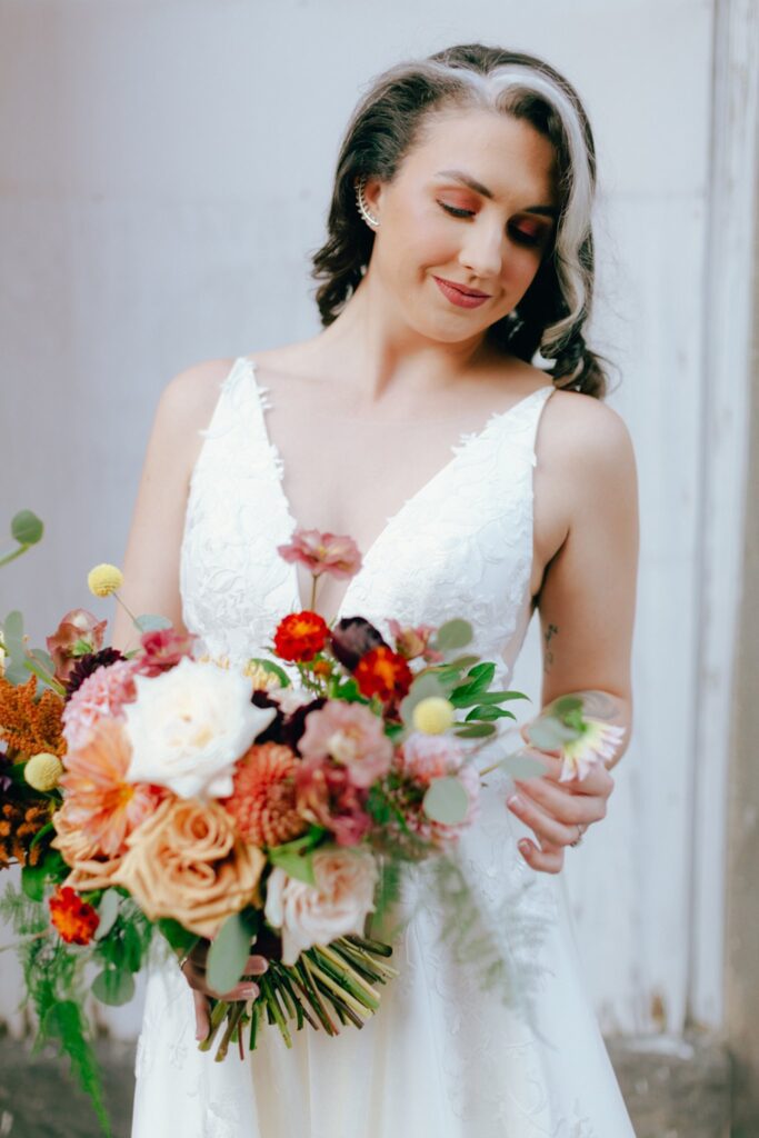 a bride looks down at her colorful wedding bouquet
