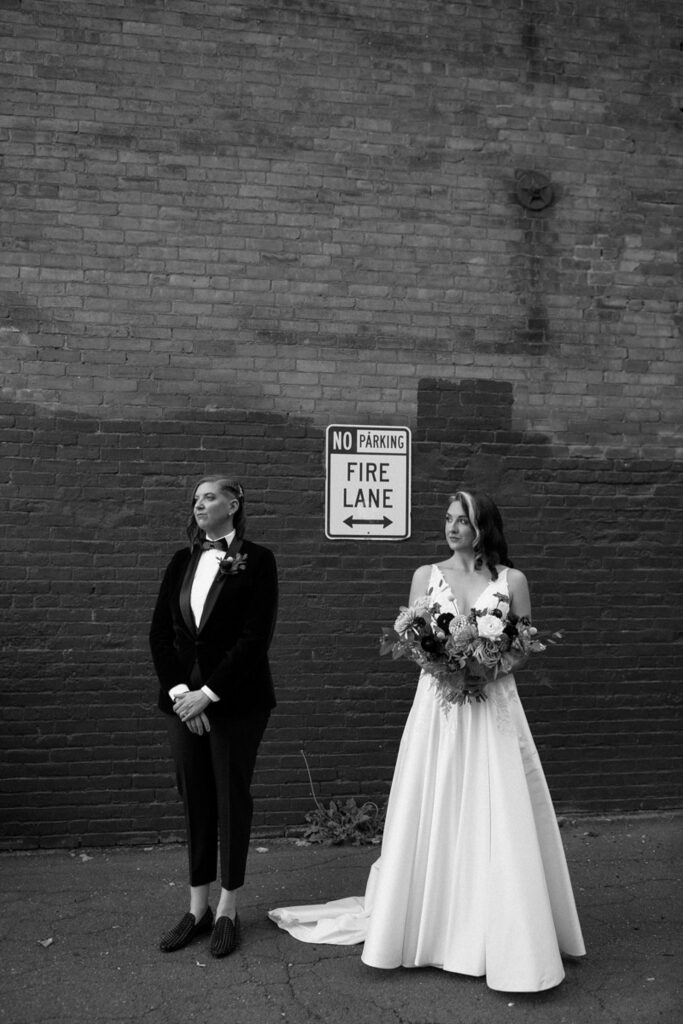 brides take a portrait in front of a brick wall