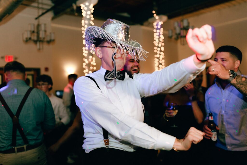 a bride dances while wearing a silver hat