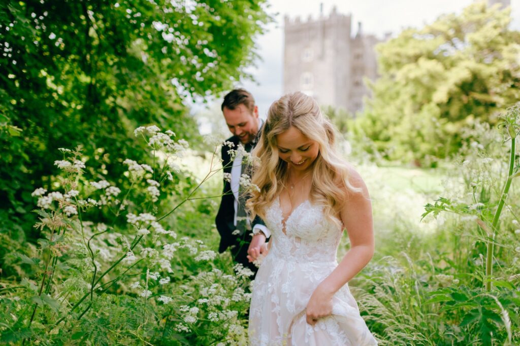 a bride leads a groom through a field in Ireland