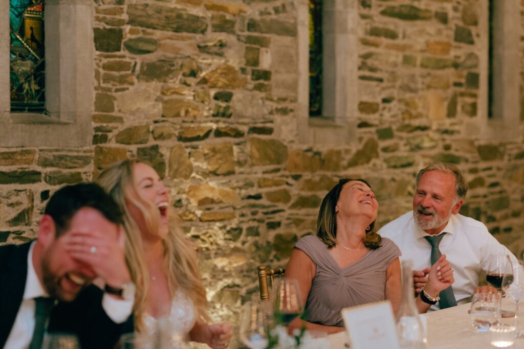 a couple and wedding guests laugh during wedding toasts