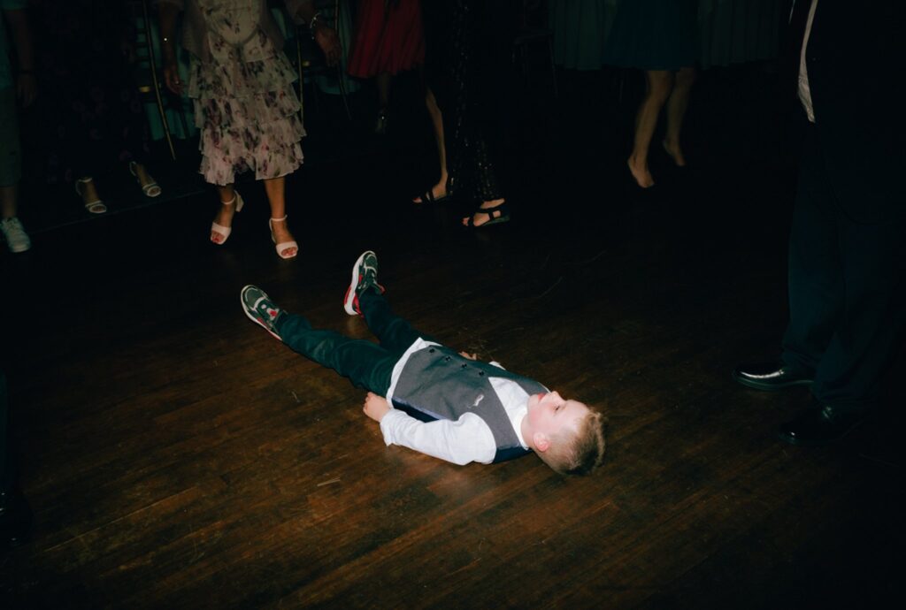a young guest lays on the floor at a wedding reception