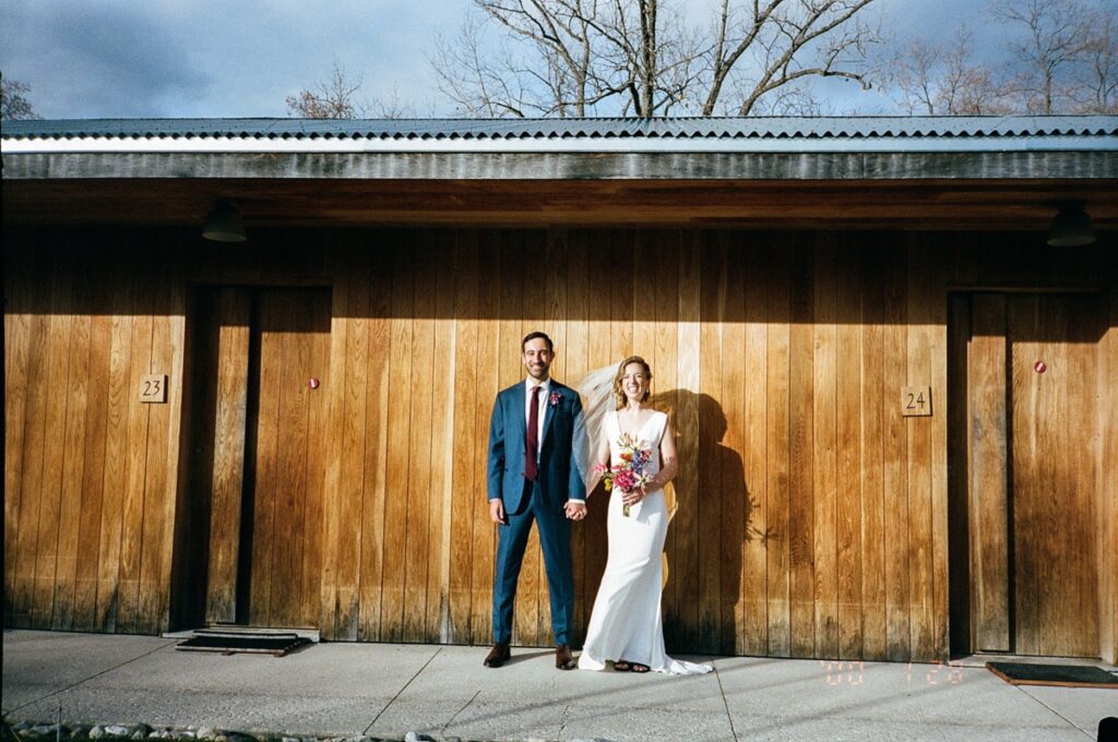 Bride and groom stand with hands clasped, captured on film