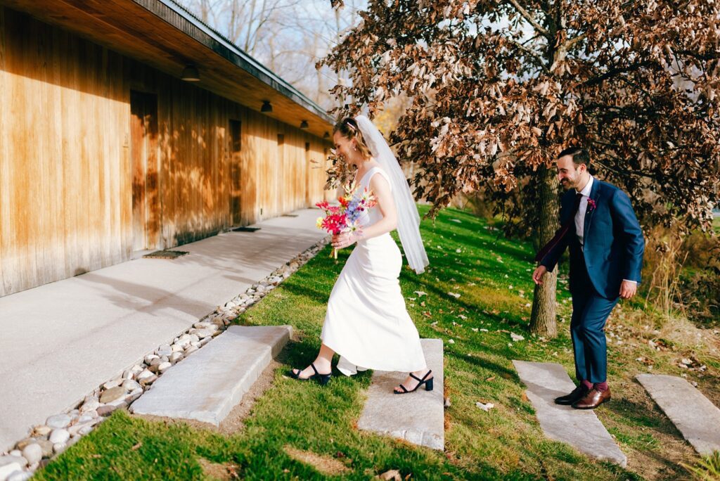 Groom follows bride up stone walkway on their New England wedding day