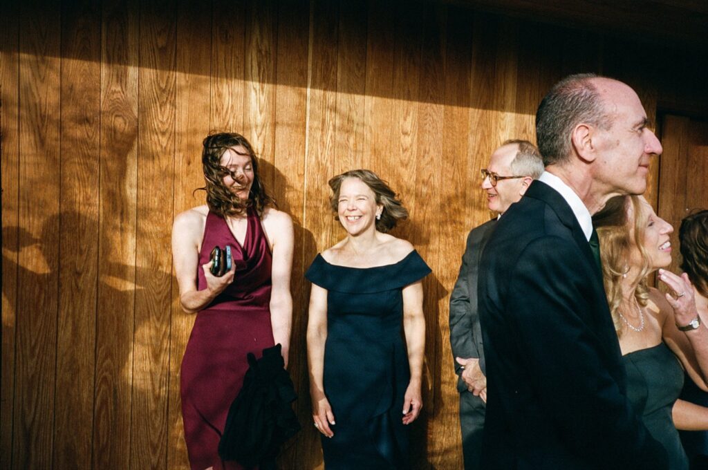 Wedding guests smile while the wind blows, captured on film