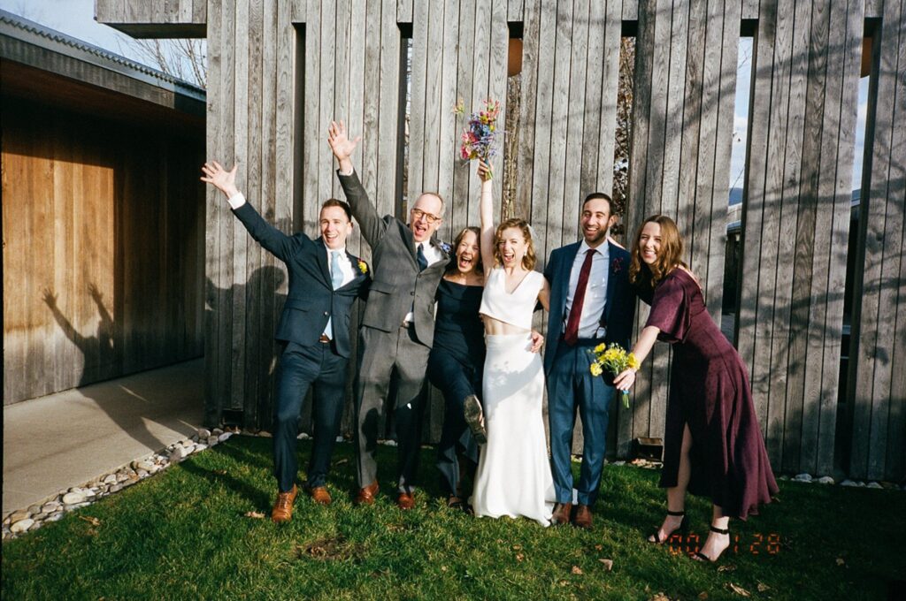 Bride and groom celebrate with their friends and family, throwing hands in the air and smiling