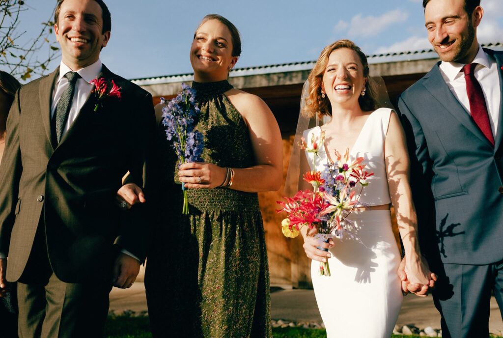 Bride and groom smile in the sun with their closest friends in Massachusetts