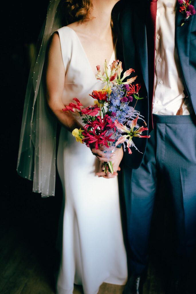 Detail film photograph of bride and groom's attire and florals