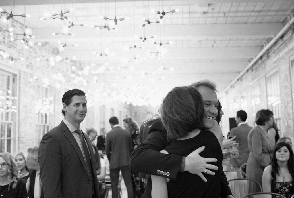 Black and white film photograph of guests hugging at Berkshires wedding