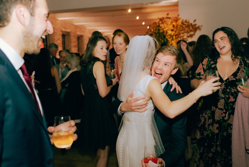 Guest screams with joy while giving the newly married bride a hug, captured on film