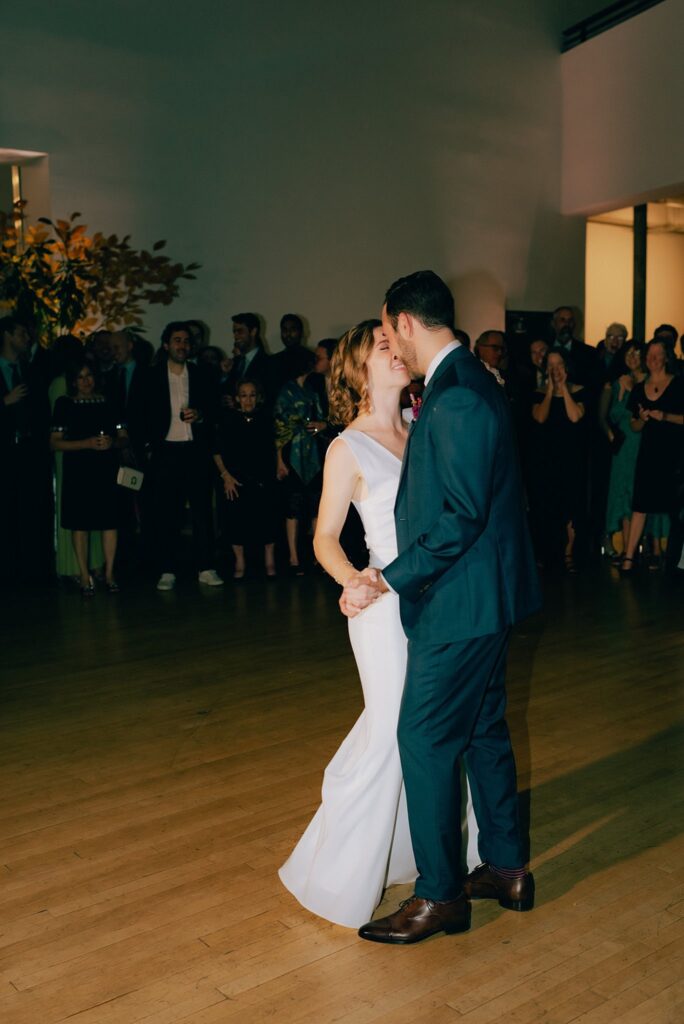 Bride and groom dance together while guests look on