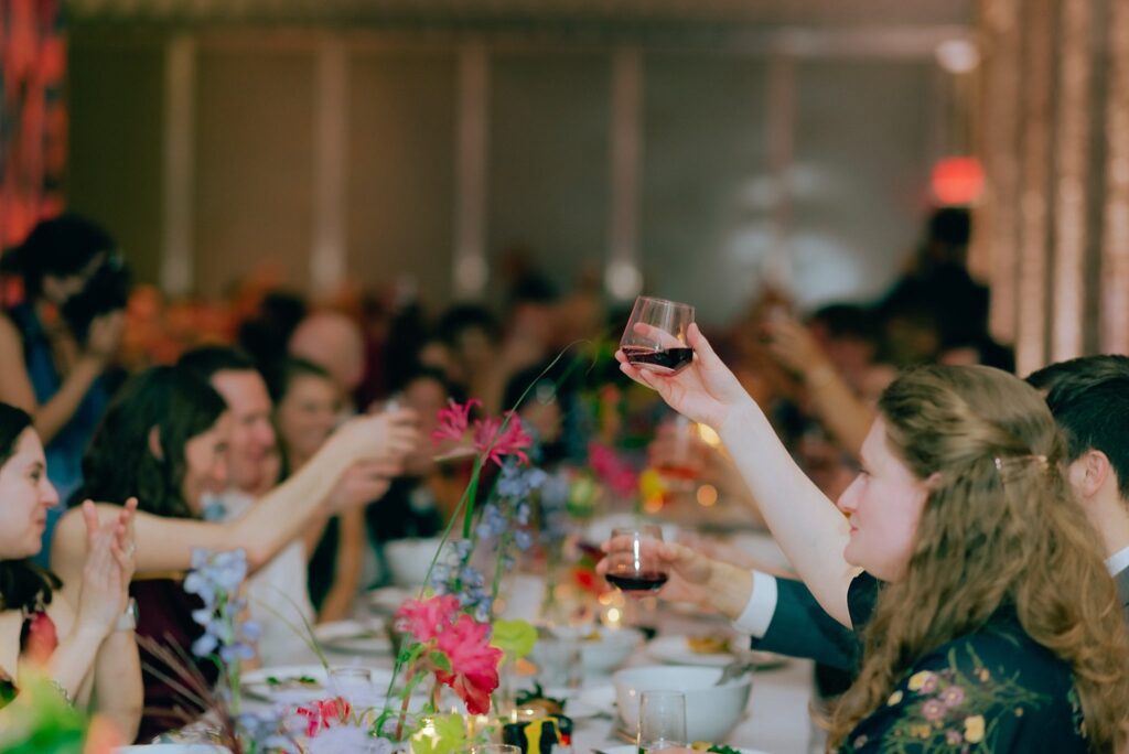 Guests raise their drinks to toast the bride and groom, captured on film