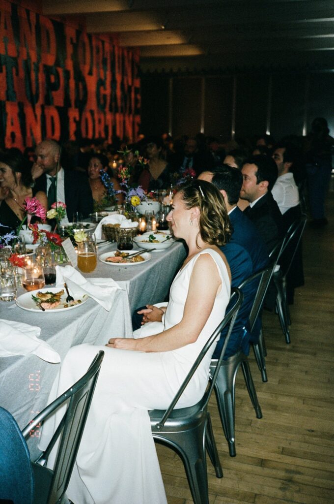 Bride smiles seated at table during wedding dinner