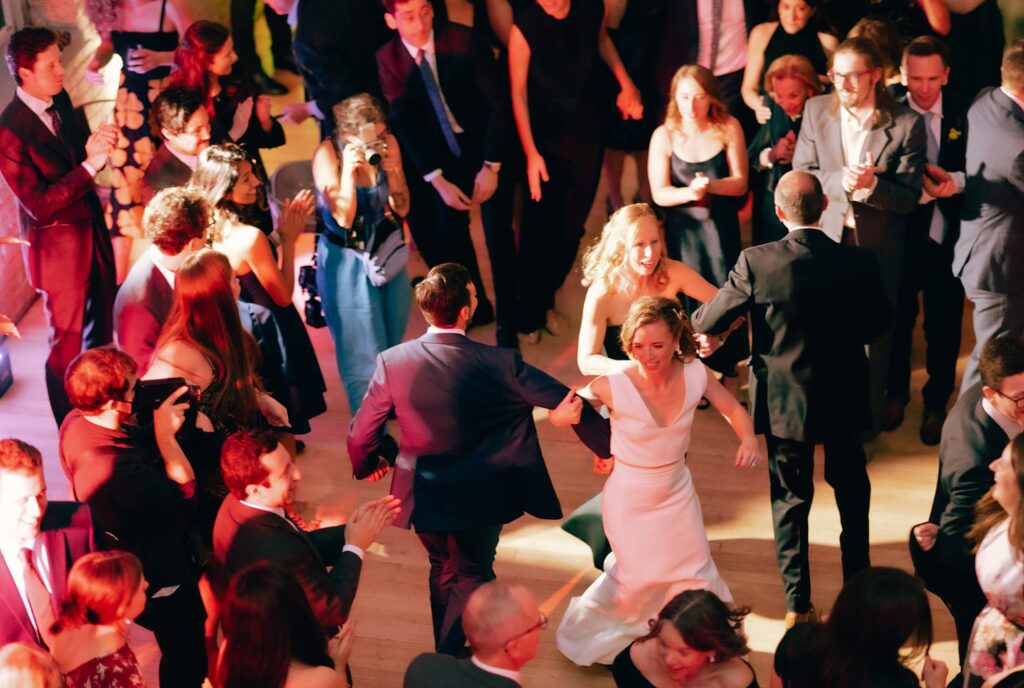 Film photograph of newly married couple and wedding guests dancing vivaciously