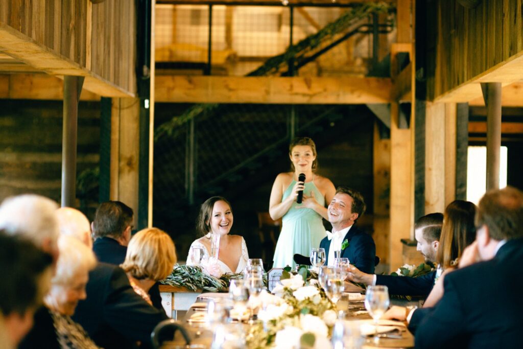 a bride and groom laugh during speeches at their wedding