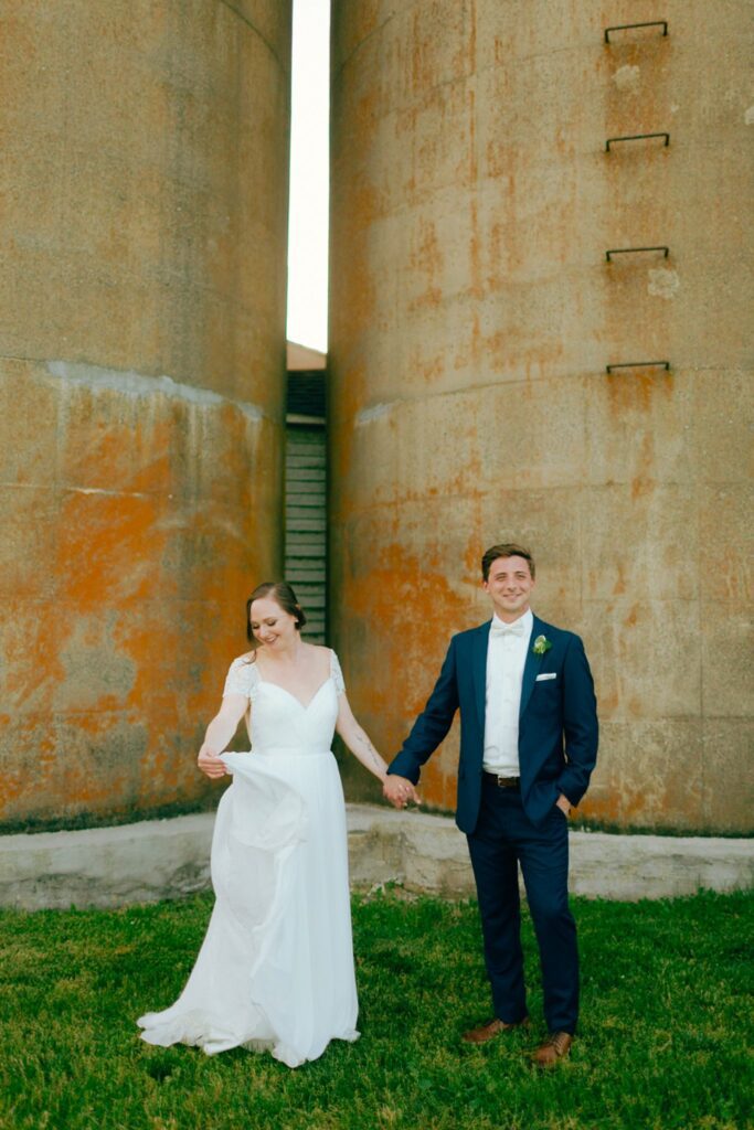 a couple poses for a photo in front of the silos at south farms