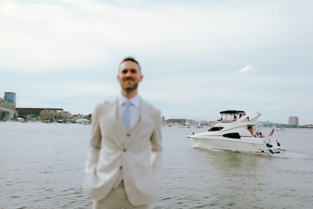 a boat drives by a groom having his portrait taken in the Seaport