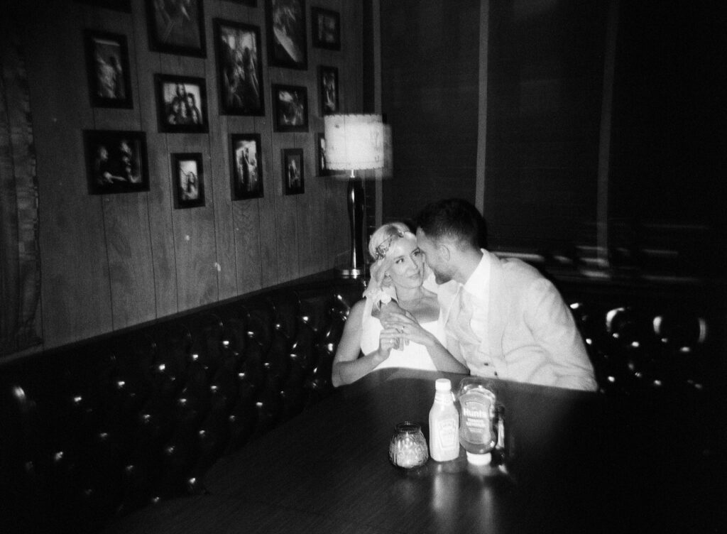 a couple snuggles in a booth at Lucky's Lounge