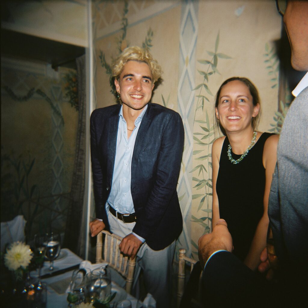 Film photo capturing the joyful expressions of wedding guests smiling and conversing at their dinner table during the reception.