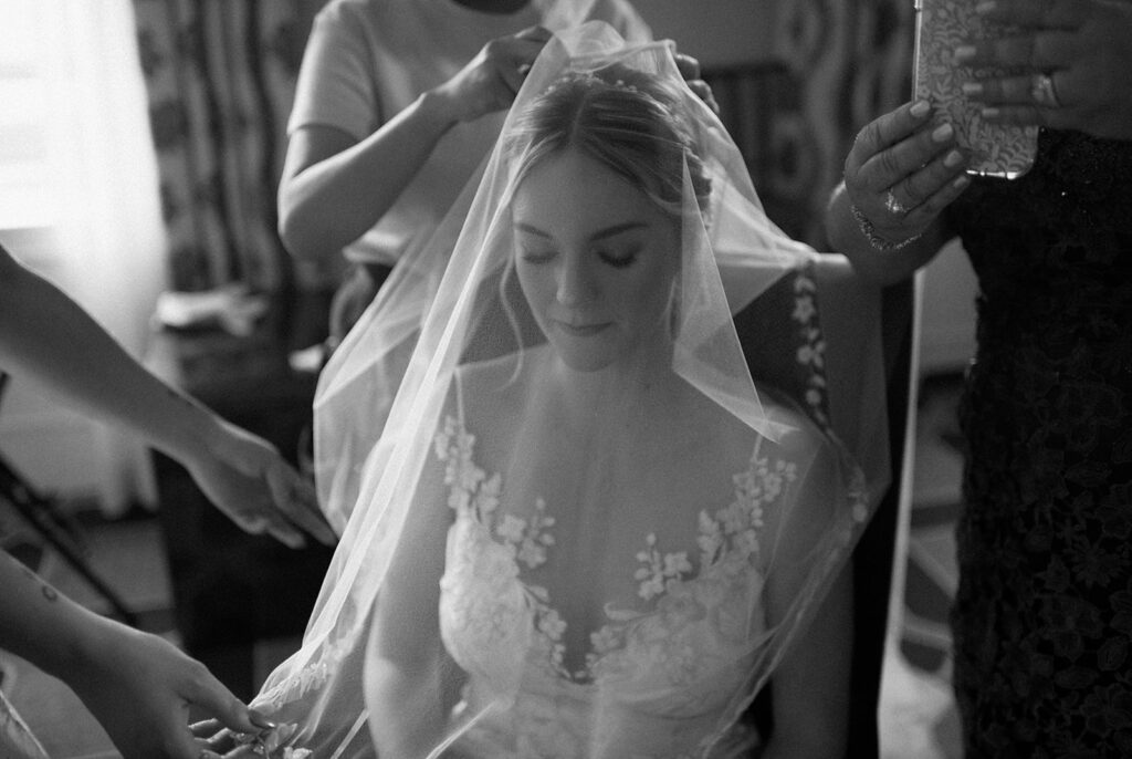 dramatic black and white film portrait of bride getting her veil added