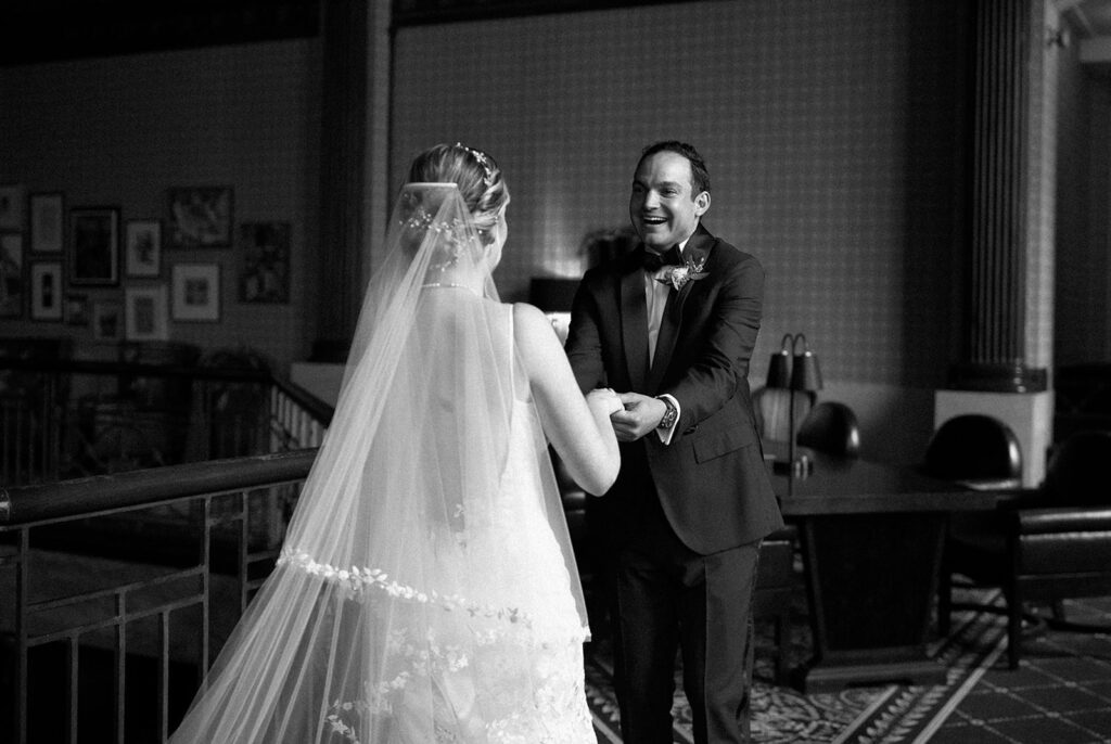 Black and white film still of groom excitedly looking at his new bride on their wedding day
