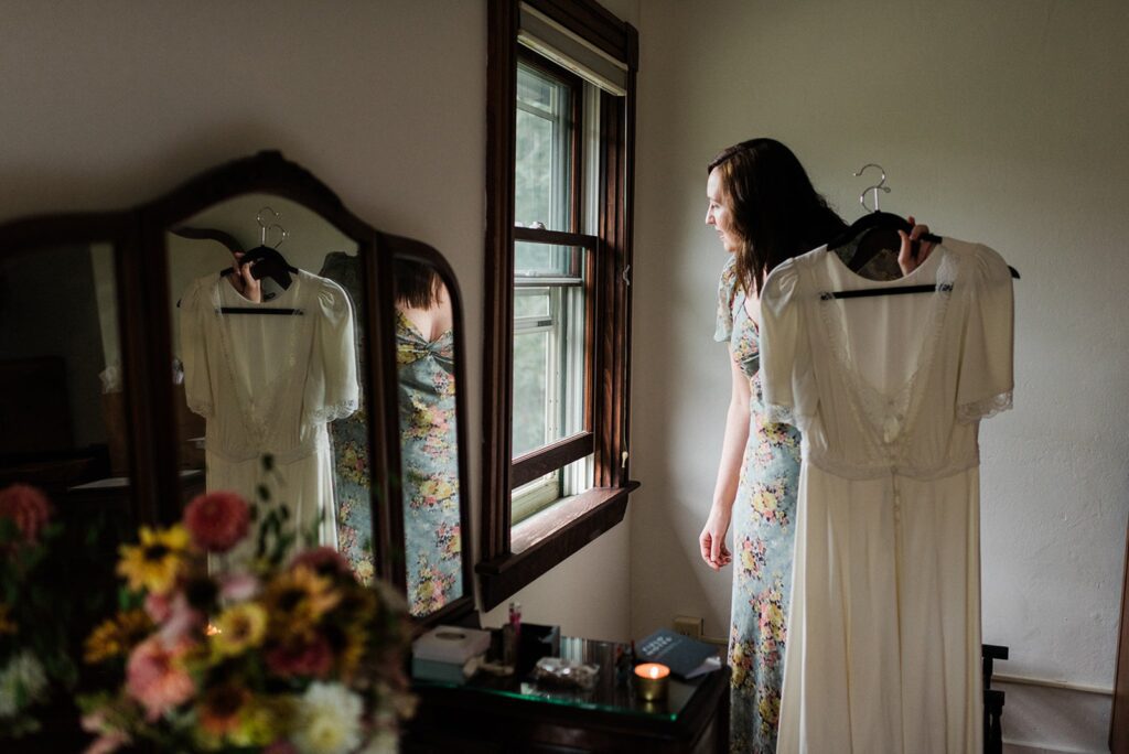 a bridesmaid holds the wedding dress for the bride