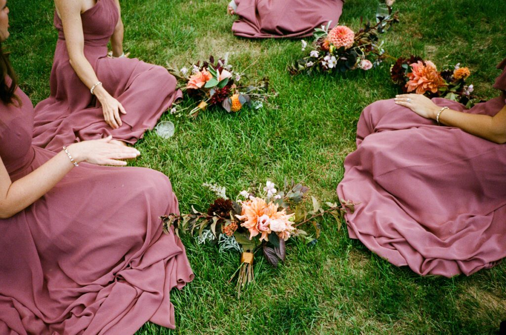 Bridesmaids sit in a field at Gloriosa & Co. in the Berkshires