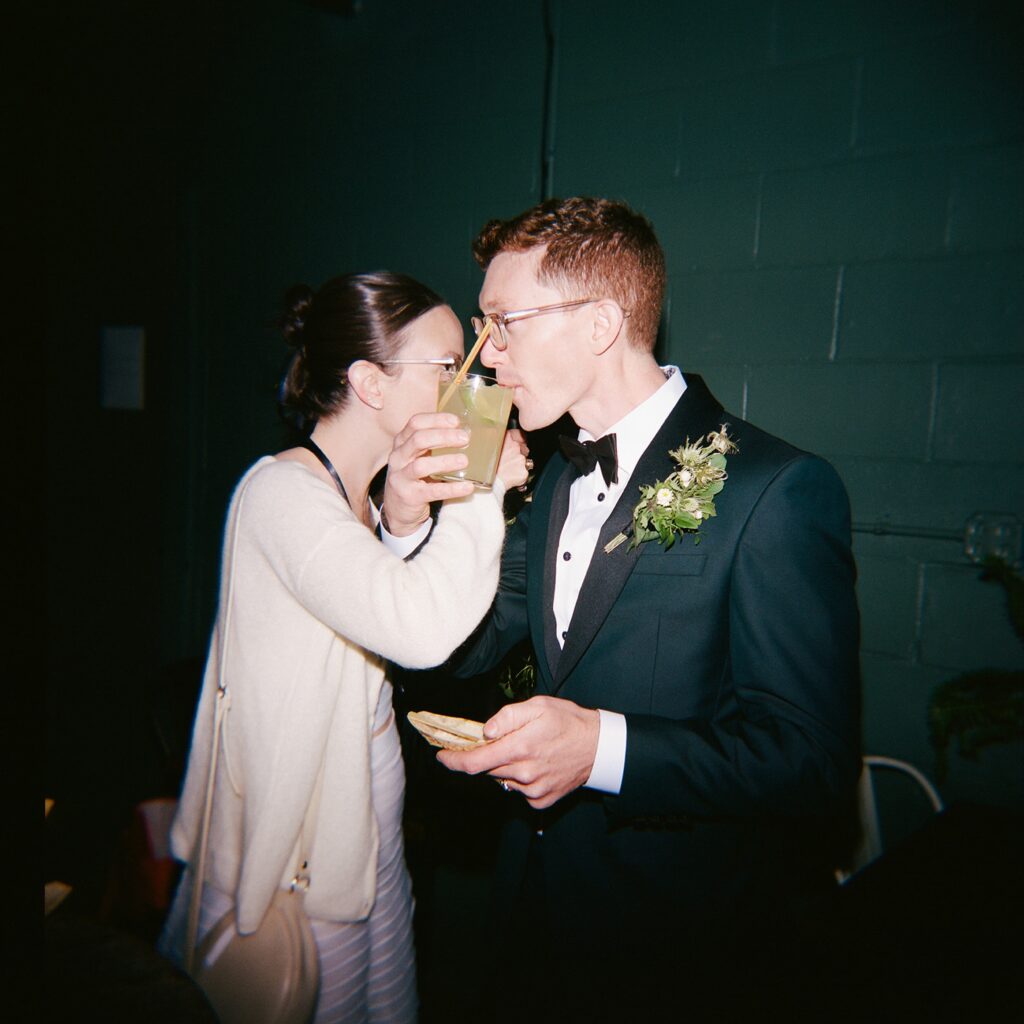 Candid film photo of bride and groom sharing a drink