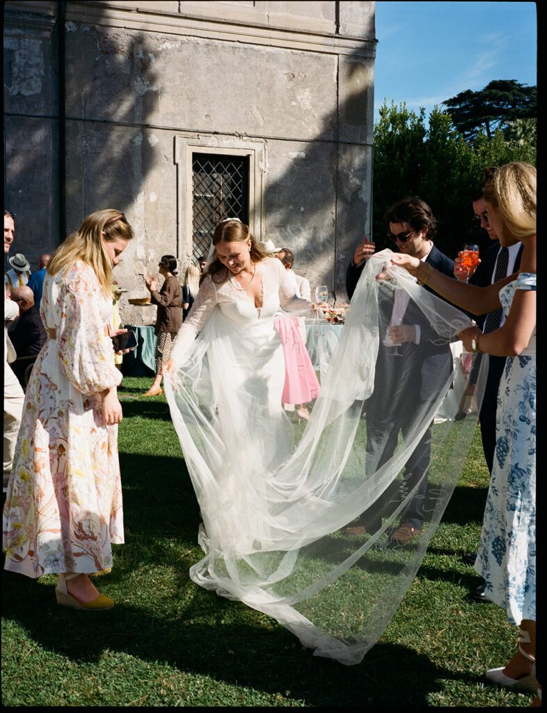 a bride shows off her veil to her friends