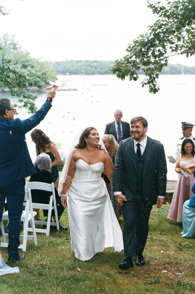 a bride and a groom recessing after getting married by the ocean
