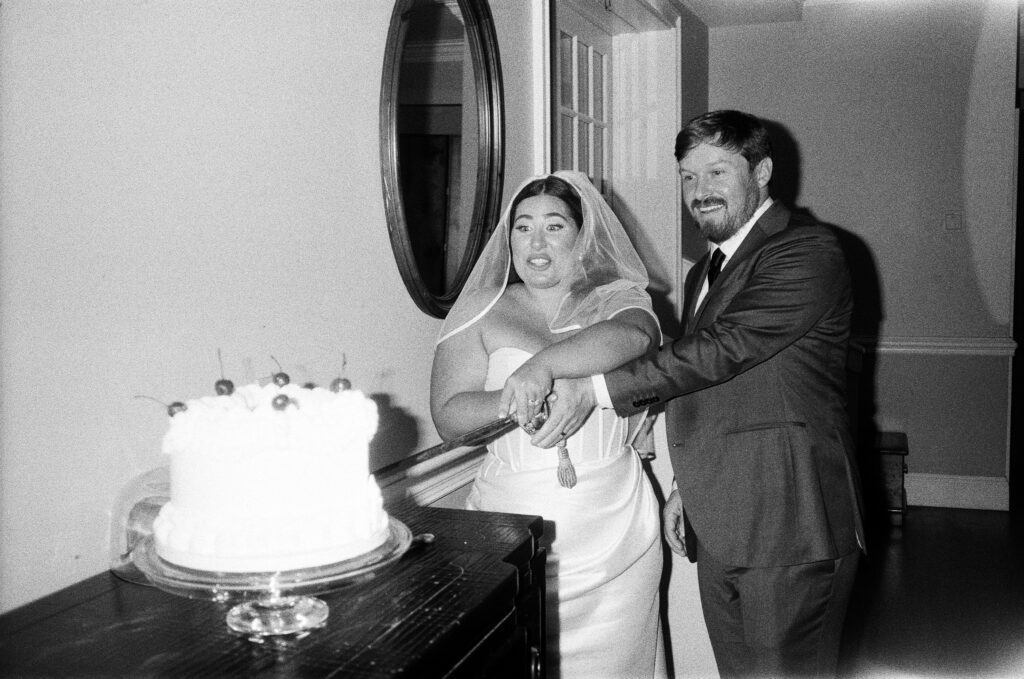 a bride and a groom cutting their cake with a sword